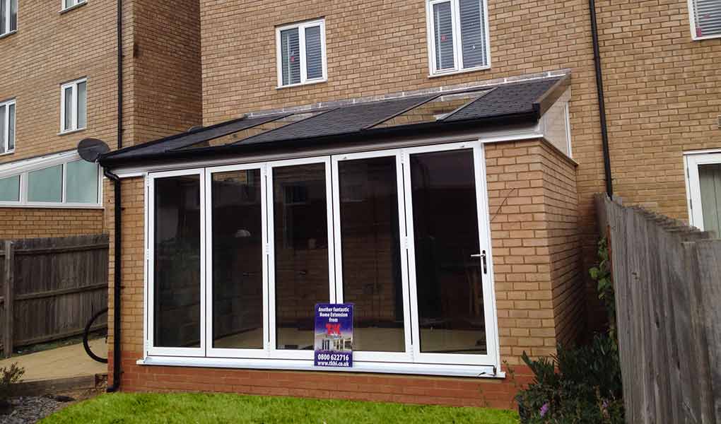 White upvc lean-to orangery leading out to a lawn