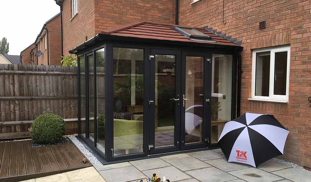 Black tiled roof Edwardian conservatory with a tiled patio